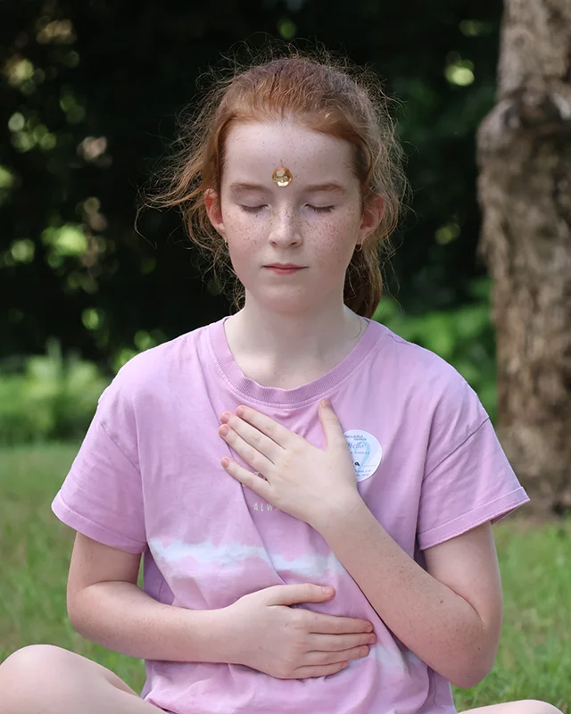 A girl with her eyes closed and her hand on her chest meditating